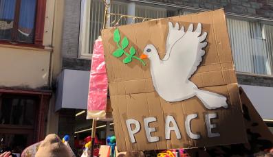 Demoschild mit Friedenstaube und Schriftzug PEACE beim Rosenmontagszug 2022 in Köln