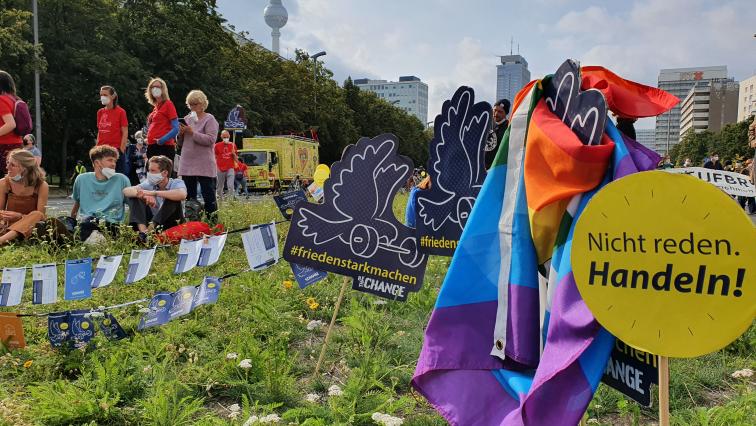 Demoschilder und PACE-Flagge auf Wiese nach der unteilbar-Demo in Berlin